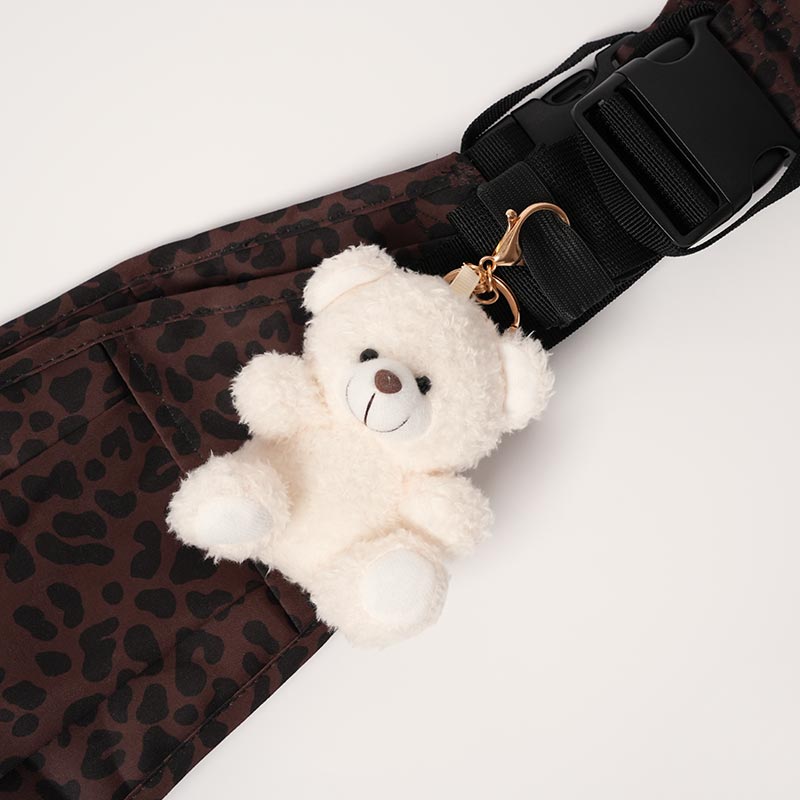 White bear charm attached onto a leopard print toddler carrier. 