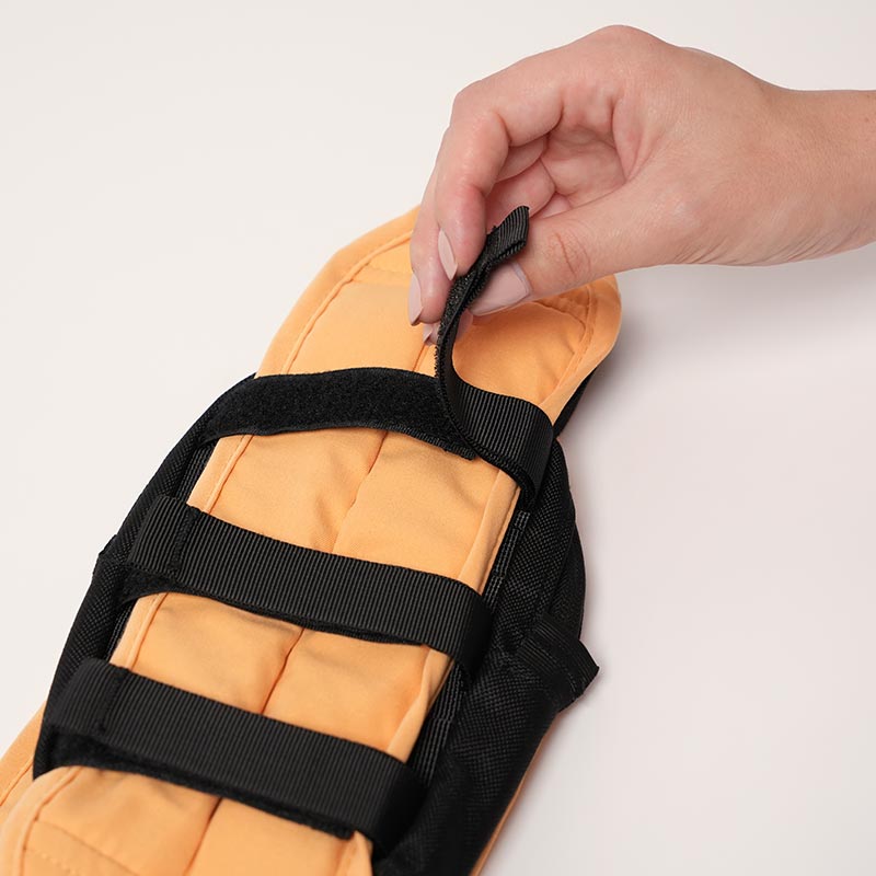 A hand adjusting zip straps of a small bag onto the toddler carrier.