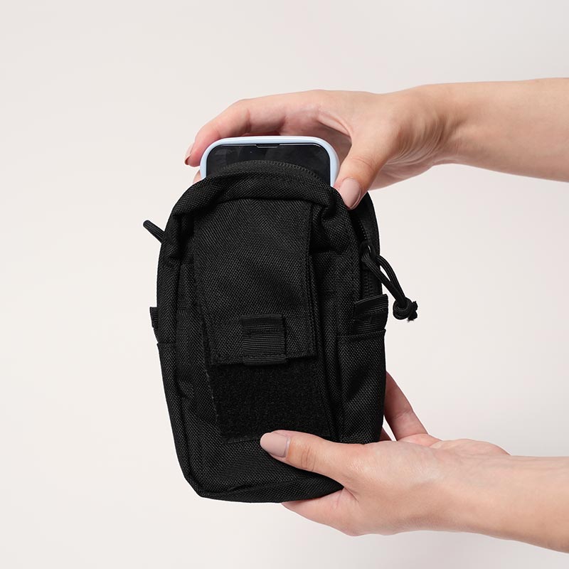 Hand placing a cellphone into a Nubioo Essentials Clip-On bag. 