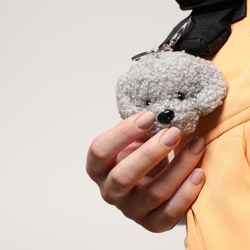 A hand holding a cute soft dog charm. 